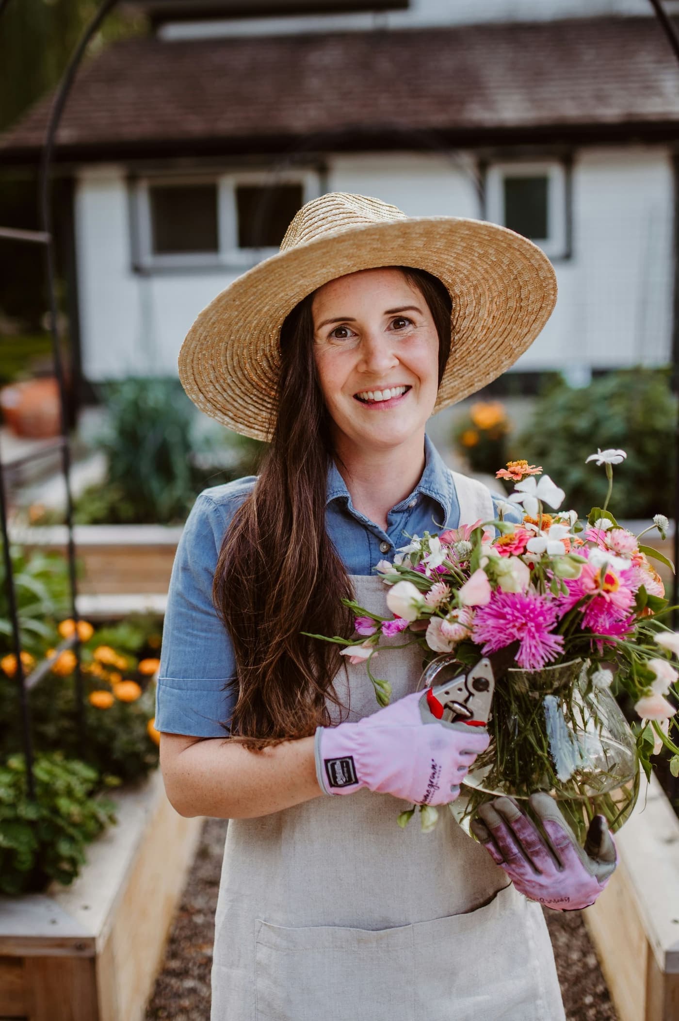 A grower in a sun hat holds a bunch of fresh-cut flowers