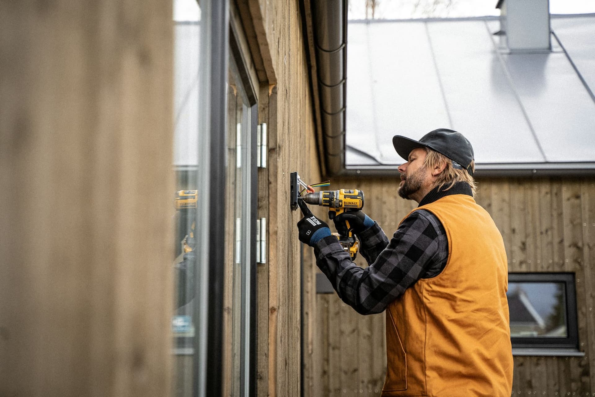 A tradesman fixes a fitting to a timber wall with a drill
